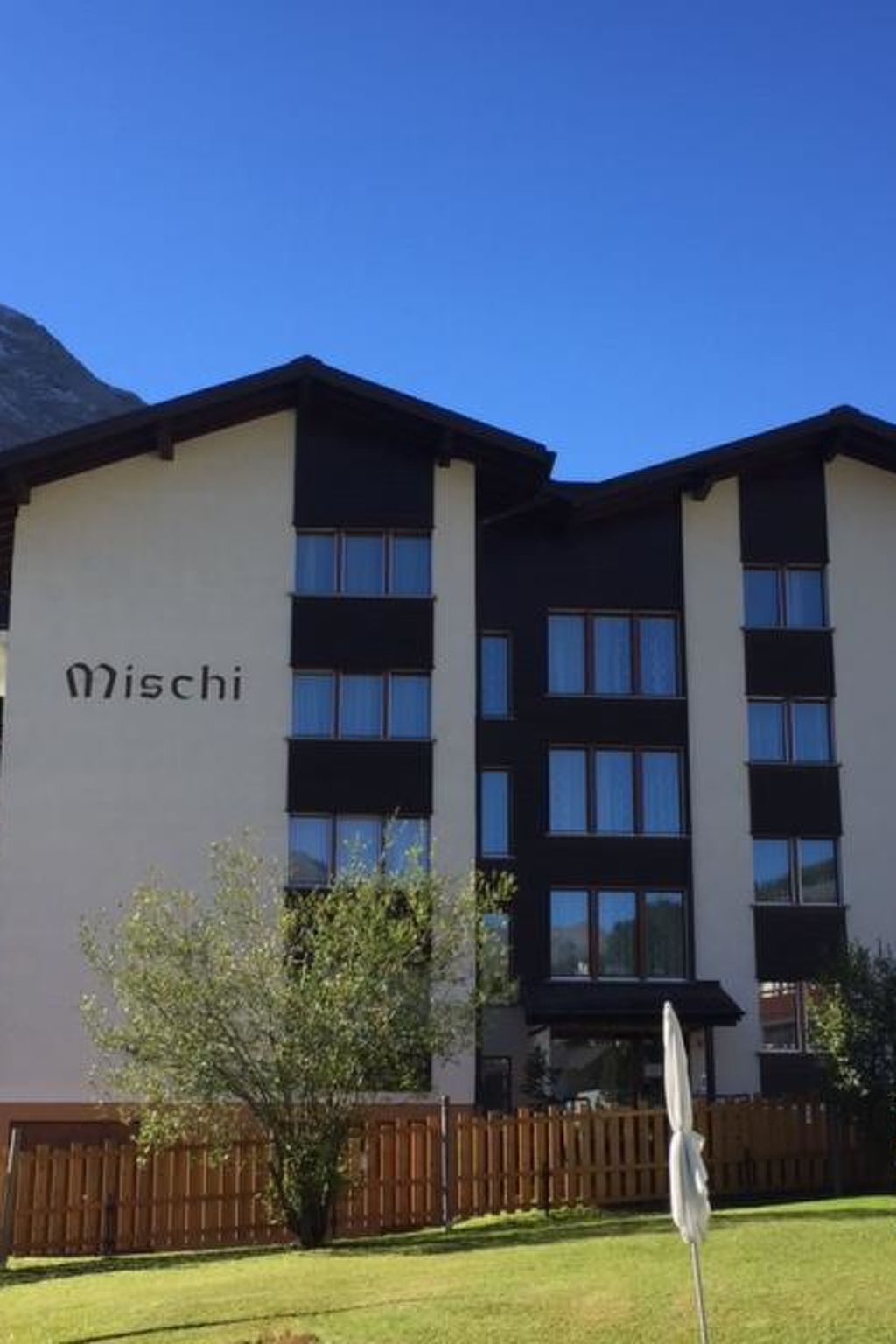 Un edificio con la scritta 'Mischi' sulla facciata, caratterizzato da uno stile architettonico moderno, diverse finestre e un tetto piatto.