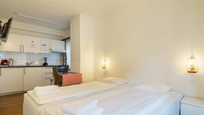 Ein Hotelzimmer mit zwei Betten, einer Küchenzeile und einer kleinen Essecke.