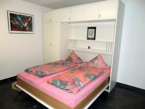 A bedroom with a bed, a wardrobe, and a painting on the wall. - Alcazar Apartments Appartement/Fewo Wohnung 6 by Interhome (Saas-Grund)