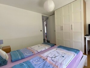 Un dormitorio con cama, armario y escritorio.