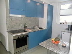 Una cocina con armarios azules, encimera de granito, estufa y lavabo.
