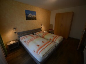 Ein Schlafzimmer mit einem Doppelbett, zwei Nachttischen, einem Schrank und einem Bild an der Wand.