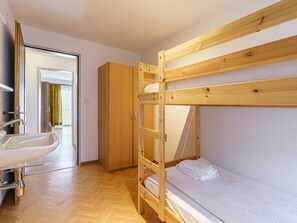 A bunk bed with a wooden frame, a white sink, and a wardrobe in a room with wooden flooring. - Haus City Appartement/Fewo Apt #3 by Interhome (Saas-Grund)