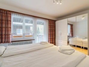Habitació d'hotel amb un llit, un armari, un mirall i una finestra amb cortines.