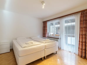 A bedroom with a double bed, a radiator, and a window with curtains. - Haus City Appartement/Fewo Apt #3 by Interhome (Saas-Grund)