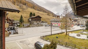 A parking lot with a mountain backdrop, a building with a wooden facade, and a clear sky. - Haus City Appartement/Fewo Apt #3 by Interhome (Saas-Grund)