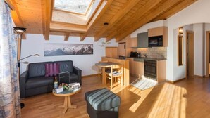 A modern interior with a wooden ceiling, a dining area, a kitchen, and a living room with a sofa and a small table. - Helvetia Apartments Appartement/Fewo Studio Nr. 2 by Interhome (Saas-Fee)