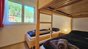 Ett rum med en våningssäng och ett fönster med utsikt över hus och grönområden.