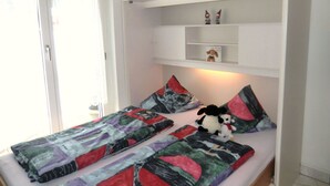 Ein Schlafzimmer mit einem Bett, Kissen, einem Nachttisch und einem Regal mit Dekoration.
