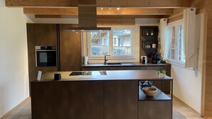Una cocina moderna con una isla central, horno empotrado y ventana con vistas a un balcón.
