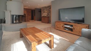 Un salon doté d’une cheminée, d’un téléviseur, de meubles en bois et d’un mur décoratif en pierre.