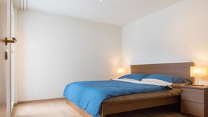 Une chambre à coucher avec un lit, des tables de chevet et une porte.