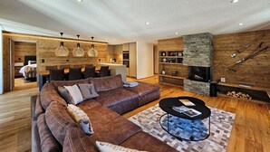 Una sala de estar moderna con un sofá de cuero marrón, una mesa redonda de centro y una chimenea de piedra.