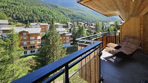 Un balcón de madera con vistas a un pueblo montañoso y casas.