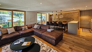 Una sala de estar moderna con un sofá modular, una zona de comedor y una cocina.