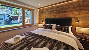 Un dormitorio con una cama grande, una ventana con vistas a edificios, paneles de madera en la pared y un cabecero.