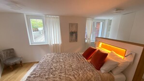 Een slaapkamer met een bed, een stoel en een raam.