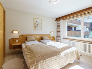 Ein Schlafzimmer mit Bett, Nachttischen, einem Fenster mit Aussicht und einem Wandbild.