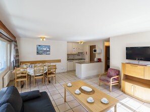 Ein gemütlicher, kleiner Wohnbereich mit Essplatz, Küchenzeile und Fernseher.