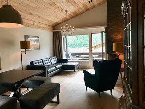 Un salon moderne avec un canapé, un fauteuil, une table et un lustre.