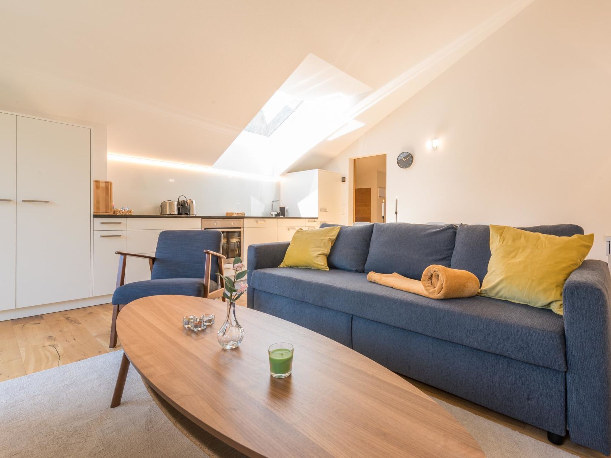 Un appartement moderne comprenant un espace de vie, une kitchenette et une fenêtre de toit.