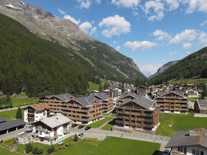 Ein Bergresort mit Chaletbauten, einem Parkplatz und Blick auf die umliegenden Berge.
