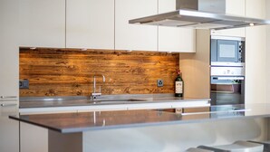 Eine moderne Küche mit Holzrückwand, Edelstahlgeräten und einer Bar mit Sitzhocker.