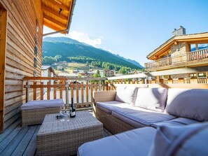 A wooden deck with wicker furniture and a view of a mountainous village. - Sonnegg Penthouse Appartement/Fewo 10-Bettwohnung by Interhome (Saas-Fee)