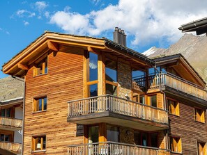 A multi-story wooden chalet with balconies, large windows, and a mountainous backdrop. - Sonnegg Penthouse Appartement/Fewo 10-Bettwohnung by Interhome (Saas-Fee)