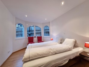 A bedroom with a large bed, two red chairs, a window with a view, and a bedside lamp. - Mountain Village Residence Appartement/Fewo Appartement/Fewo by Interhome (Saas-Fee)