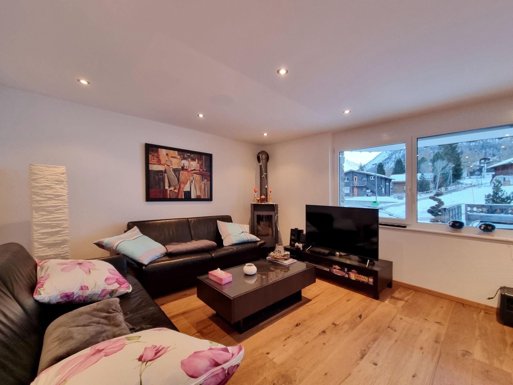 A living room with a black leather sofa, a coffee table, a flat-screen TV, and a fireplace.