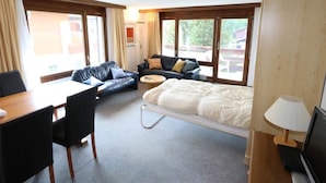 A hotel room with a bed, two sofas, a desk, and a TV. - Kontiki Appartement/Fewo 4-Bettwohnung Kontiki L by Interhome (Saas-Fee)