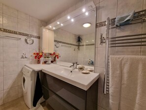 A modern bathroom with a built-in washing machine, a large mirror, and a towel rack. - Daniela 2 Appartement/Fewo Appartement/Fewo by Interhome (Saas-Fee)