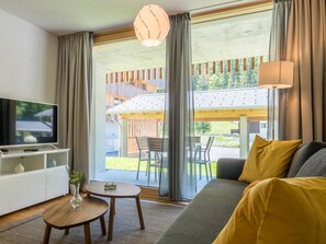 A modern living room with a sofa, television, and a dining area with a table and chairs. - Montela Apartment-Hotel & Resort - Holiday Stay Appartement/Fewo by Interhome (Saas-Grund)