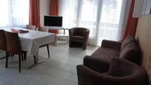 A modern living room with a dining area, a flat-screen TV, and large windows with curtains. - Mischi 9 & 10 Appartement/Fewo 5-Bettwohnung Nr. 9 by Interhome (Saas-Fee)