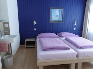 A room with two beds, a sink, and a small table. - Mischi 9 & 10 Appartement/Fewo 5-Bettwohnung Nr. 9 by Interhome (Saas-Fee)