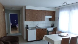 A compact kitchen with wooden cabinets, a sink, and a dining area with a table and chairs. - Mischi 9 & 10 Appartement/Fewo 5-Bettwohnung Nr. 9 by Interhome (Saas-Fee)