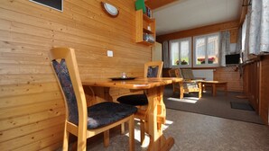 Un interior de madera con una mesa de comedor, sillas, un televisor y una ventana con cortinas.