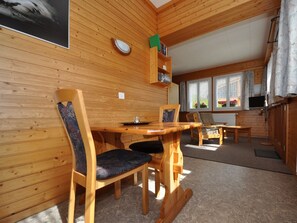 A wooden interior with a dining table, chairs, a television, and a window with curtains. - Chalet Ideal Appartement/Fewo 2-Bettwohnung Nr. 1 by Interhome (Saas-Fee)