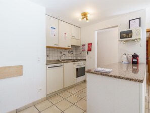 Ett kompakt kök med diskmaskin, ugn och mikrovågsugn placerade på en bänkskiva.