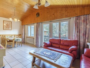 Ein gemütliches Wohnzimmer mit einem roten Ledersofa, einem Holztisch und einem Essbereich mit Tisch und Stühlen.