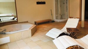 Een badkamer met een ruim bad, een douchecabine en twee comfortabele fauteuils.