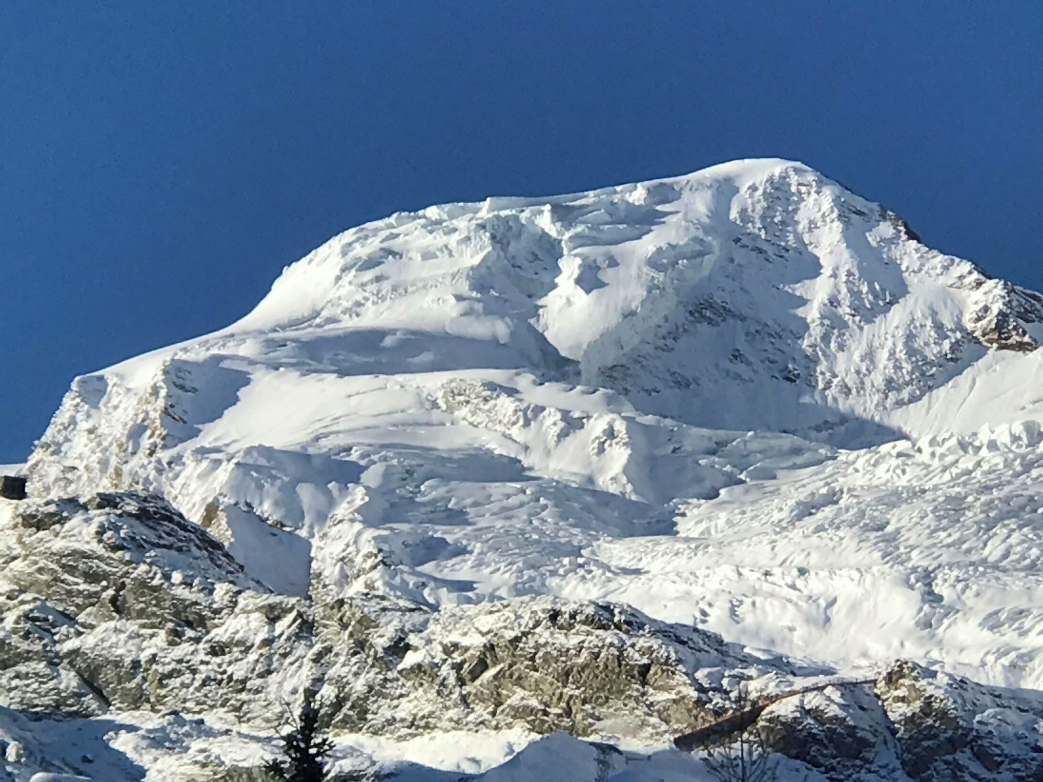 Ein mit Schnee bedeckter Berg mit blauem, wolkenlosem Himmel.
