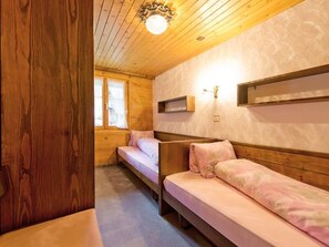 Ein Holzblockhaus-Interieur mit zwei Stockbetten, einer kleinen Ablage und einem Fenster.