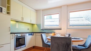 A modern kitchen with a built-in oven, a dining table with chairs, and large windows. - Dolce Vita Appartement/Fewo 2-Bettwohnung Südlenz by Interhome (Saas-Fee)