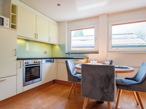 A modern kitchen with a built-in oven, a dining table with chairs, and large windows. - Dolce Vita Appartement/Fewo 2-Bettwohnung Südlenz by Interhome (Saas-Fee)