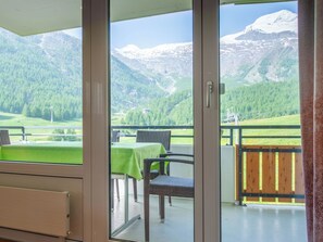 A room with a sliding glass door leading to a balcony with a view of mountains and a green landscape. - Dolce Vita Appartement/Fewo 2-Bettwohnung Südlenz by Interhome (Saas-Fee)