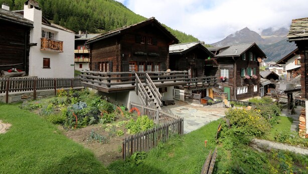 En traditionel bjerglandsby med træhuse, en stentrappe og en have.