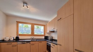 Eine moderne Küche mit Holzausstattung, einem eingebauten Backofen und einem Fenster für natürliches Licht.