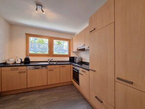 Eine moderne Küche mit Holzausstattung, einem eingebauten Backofen und einem Fenster für natürliches Licht.